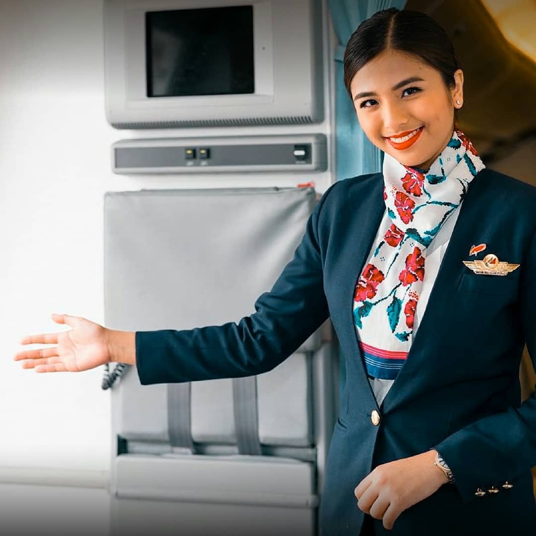 Philippine Airlines female cabin crew welcoming passengers.
