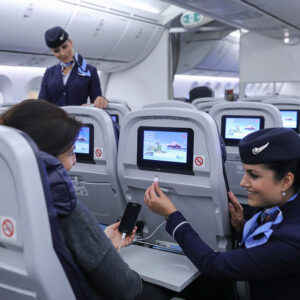 TUI female Flight Attendant assisting a passenger.