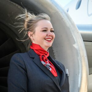 Helvetic Airways female Cabin Crew in front of an engine.