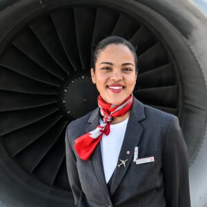 Helvetic Airways female Flight Attendant in front of plane's engine.