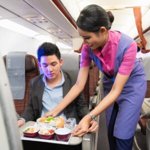 Thai Airways female Cabin Crew serving a passenger.